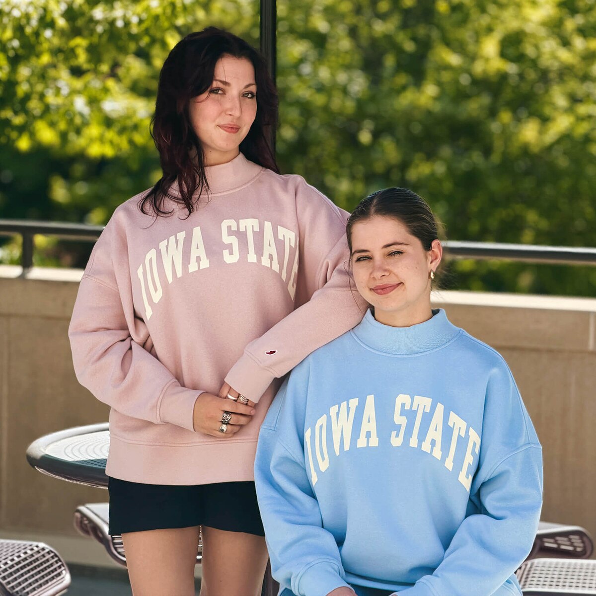 A student wearing League Women's Iowa State Dusty Pink Mock Neck Crew Sweatshirt with another student wearing the matching blue version